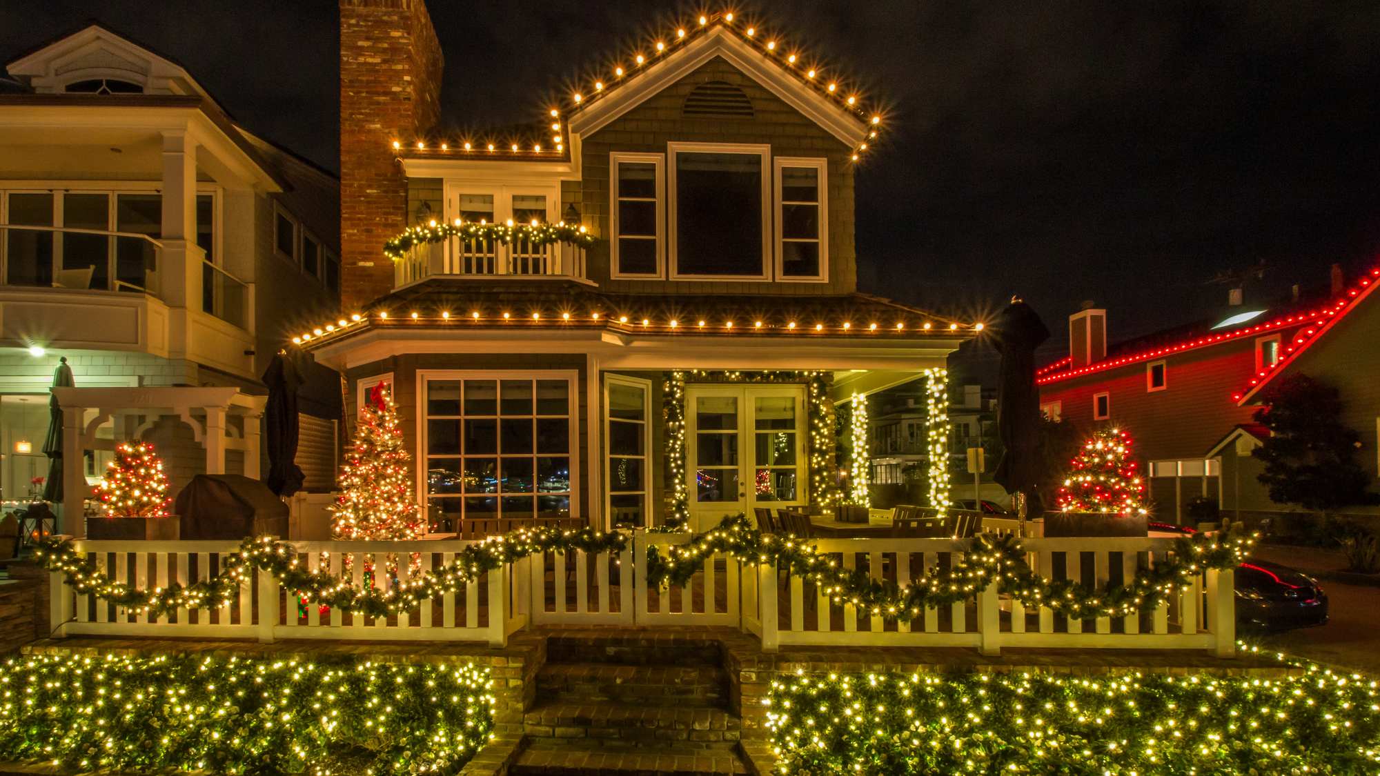 A house at night with warm white lights along the roofline