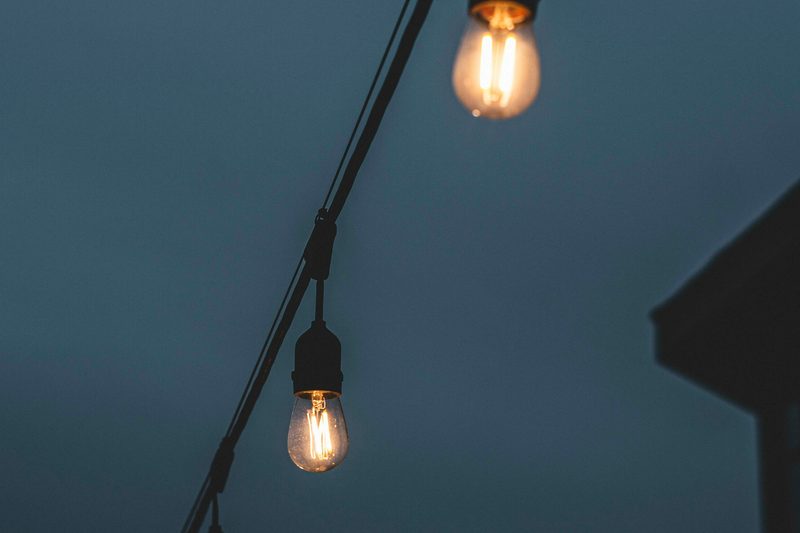 A close up of a warm white bulb strand along a roof edge